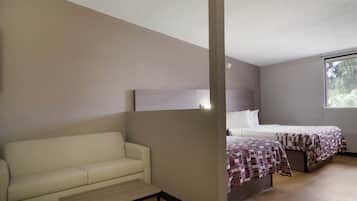 A room with a sofa, two beds with checkered bedding, a window, and a wall-mounted light fixture.