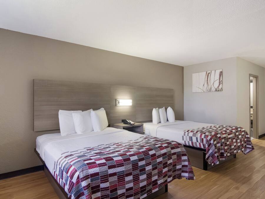 Habitación de hotel con dos camas, una mesita de noche, un teléfono y un cuadro en la pared.
