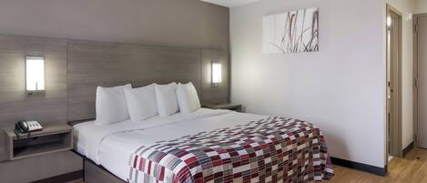 A modern hotel room with a large bed, bedside tables, a phone, and a painting on the wall.