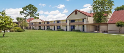 Un hotel a più piani con tetto piano e un prato curato in primo piano.