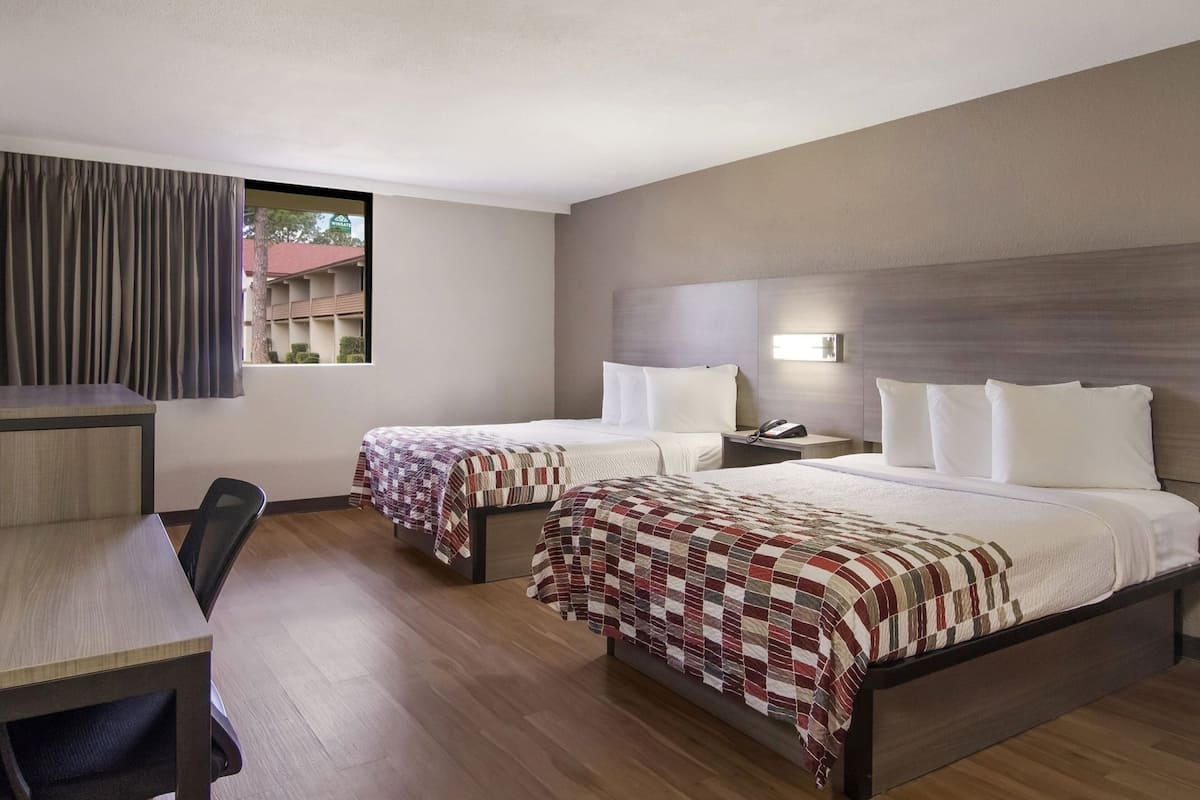 Ein Hotelzimmer mit zwei Betten, einem Schreibtisch und einem Stuhl.