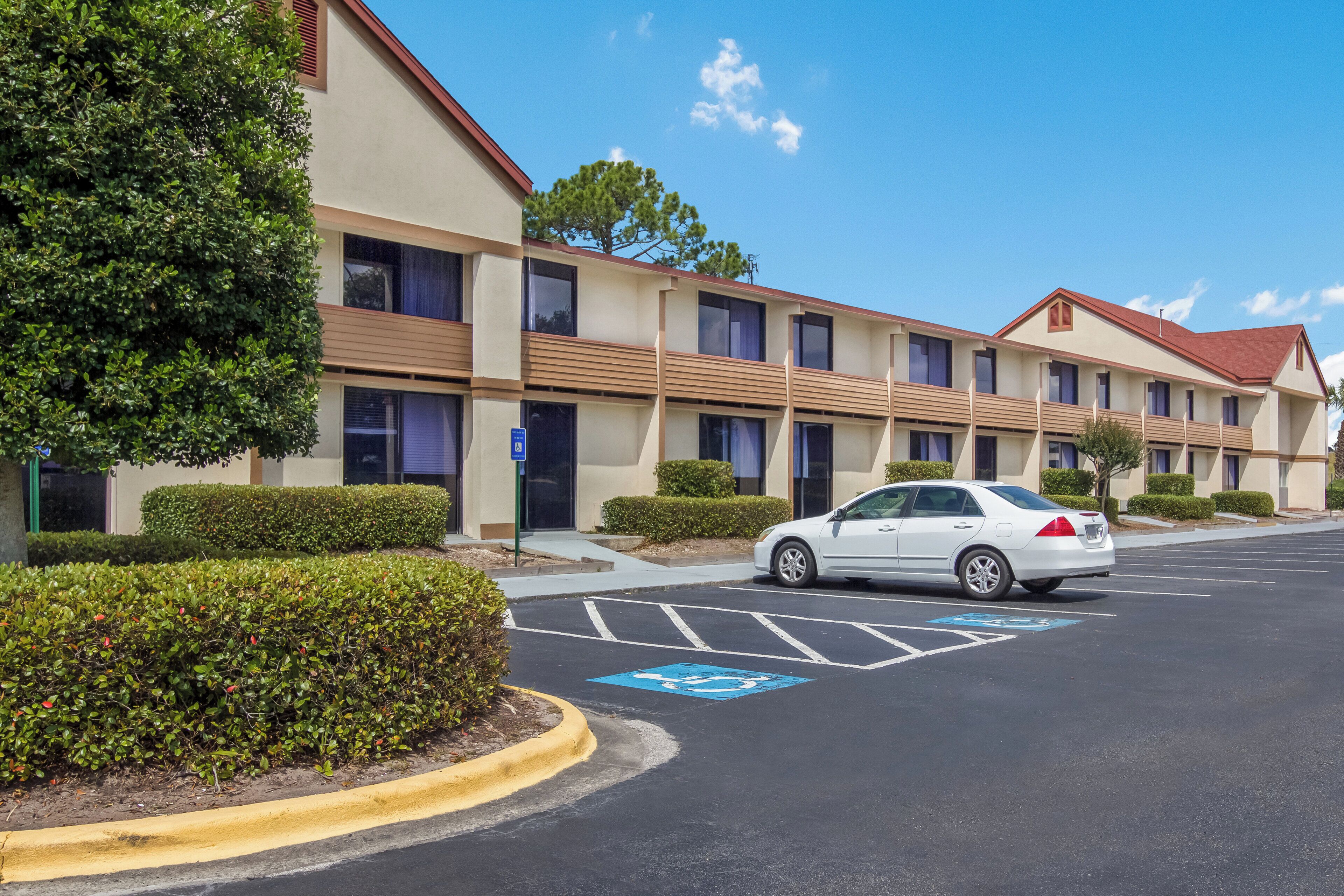Un hôtel à plusieurs étages doté d’un parking, comprenant une place de stationnement réservée aux personnes handicapées.