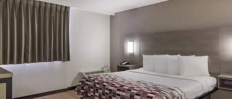 Quarto de hotel com cama, mesa de cabeceira, telefone e janela com cortinas.