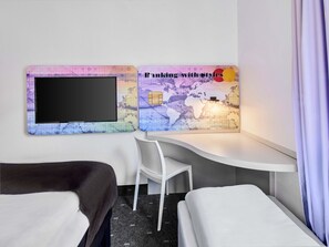 Una habitación de hotel con dos camas, un escritorio y un televisor montado en la pared.
