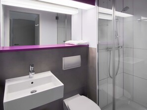 Un baño moderno con un lavamanos blanco, un espejo y una cabina de ducha de vidrio.
