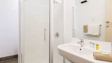 A modern bathroom with a glass-enclosed shower, a white sink, and a mirror above it.