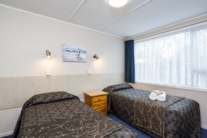 A hotel room with two beds, a small wooden nightstand, a painting on the wall, and a window with curtains. - Comfort Inn Tayesta (Invercargill)