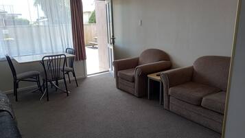 A living room with a sofa, armchair, and dining table with chairs.