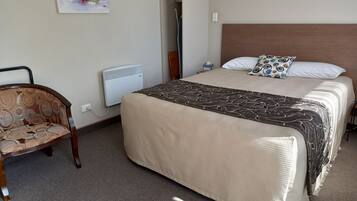 Ein Hotelzimmer mit Bett, Stuhl, Heizung und einem Bild an der Wand.