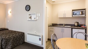 A compact hotel room with a bed, a small kitchenette, a dining table, and a chair. - Comfort Inn Tayesta (Invercargill)