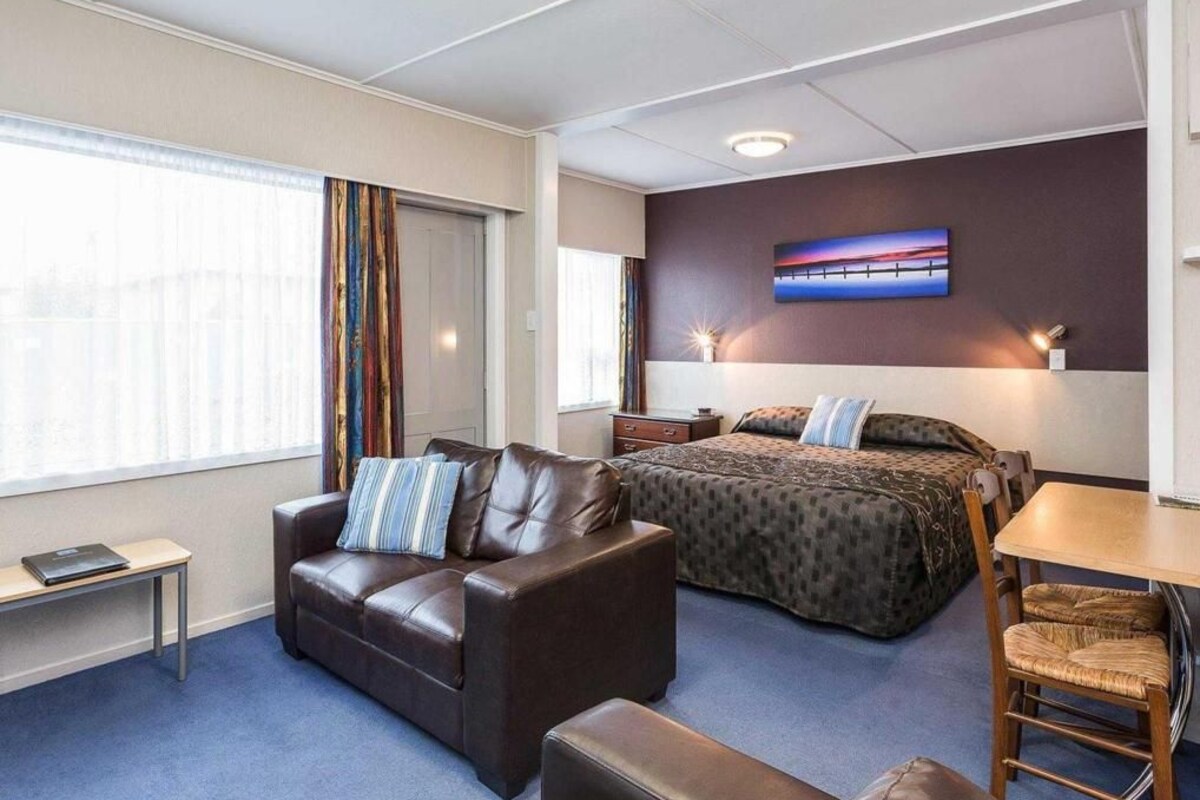A hotel room with a bed, a sofa, a desk, and a chair.