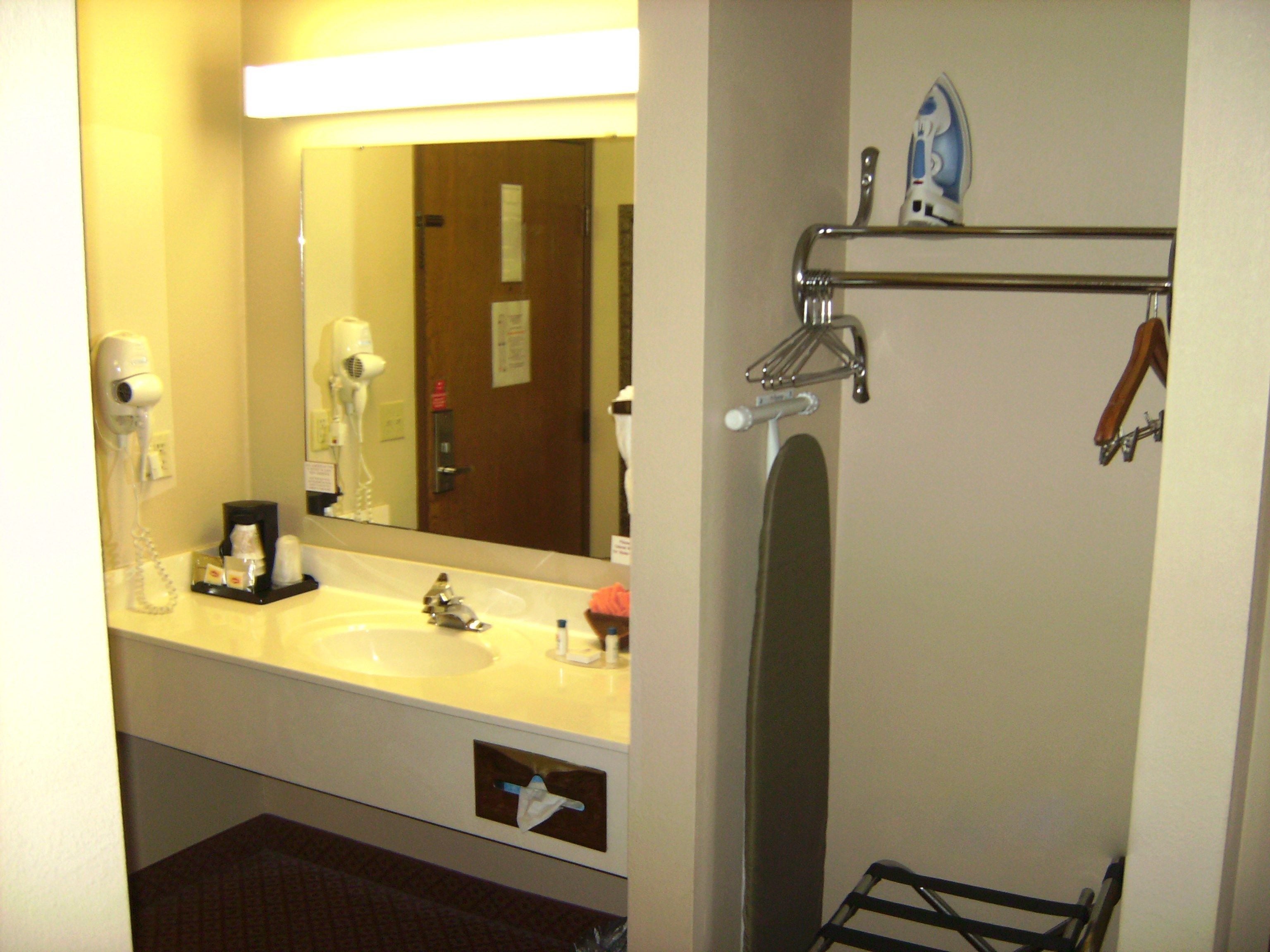 A bathroom with a sink, mirror, hair dryer, and towel rack.