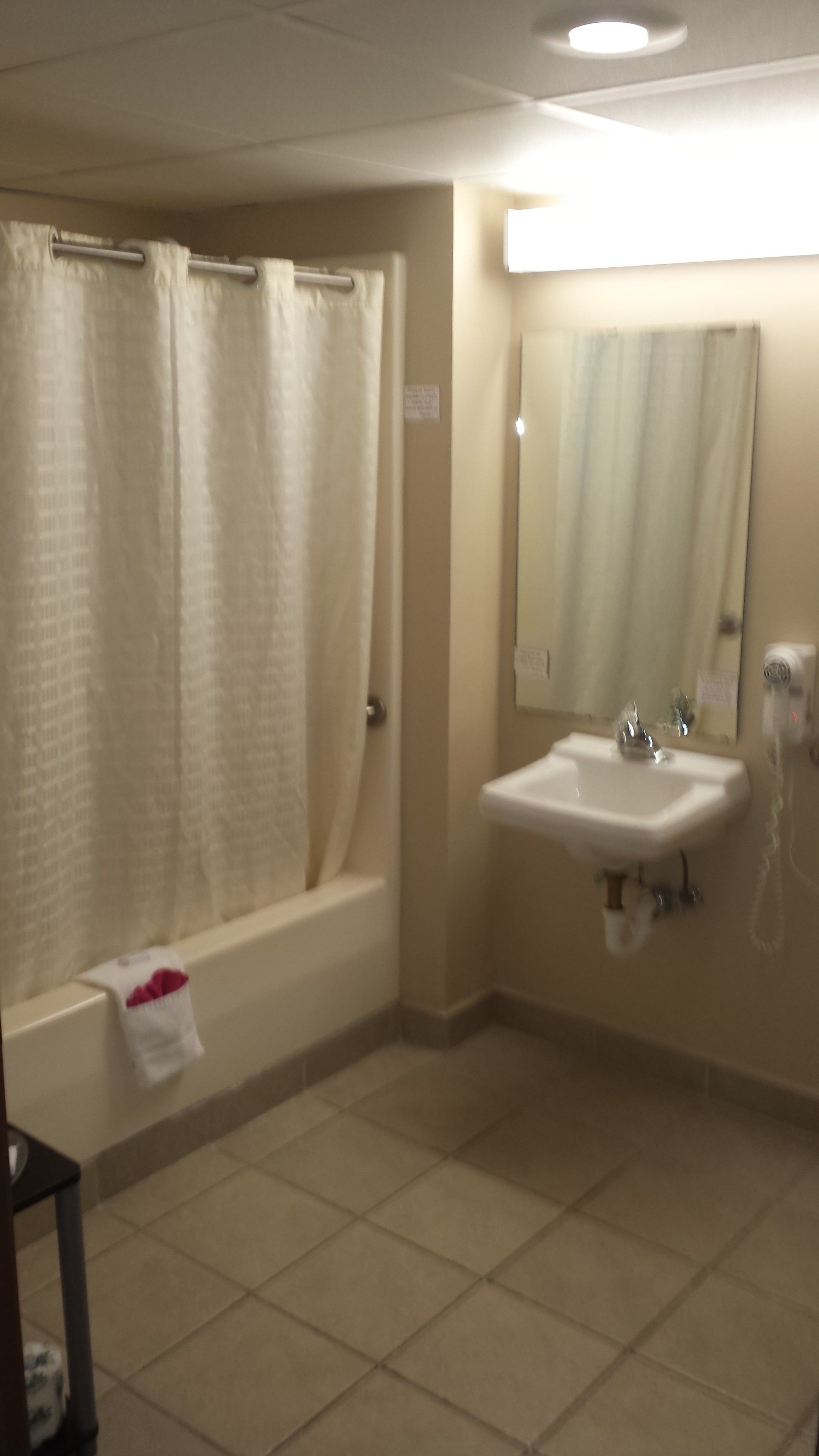 A bathroom with a bathtub, a sink, and a mirror.