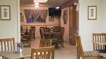 A dining area with wooden tables and chairs, a television mounted on the wall, and a sign indicating the room as 'House PH'.