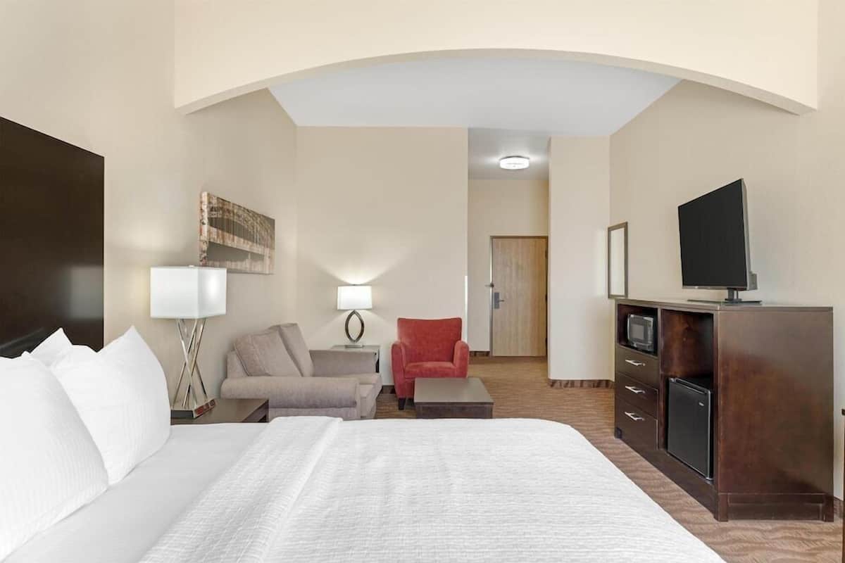 A hotel room with a bed, a desk, a TV, and a chair.