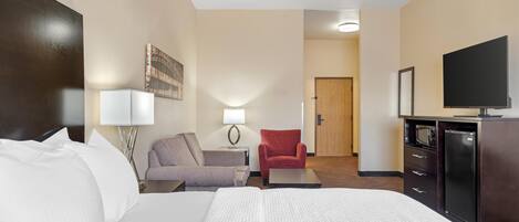 Habitación de hotel con cama, escritorio, silla, televisor y puerta.