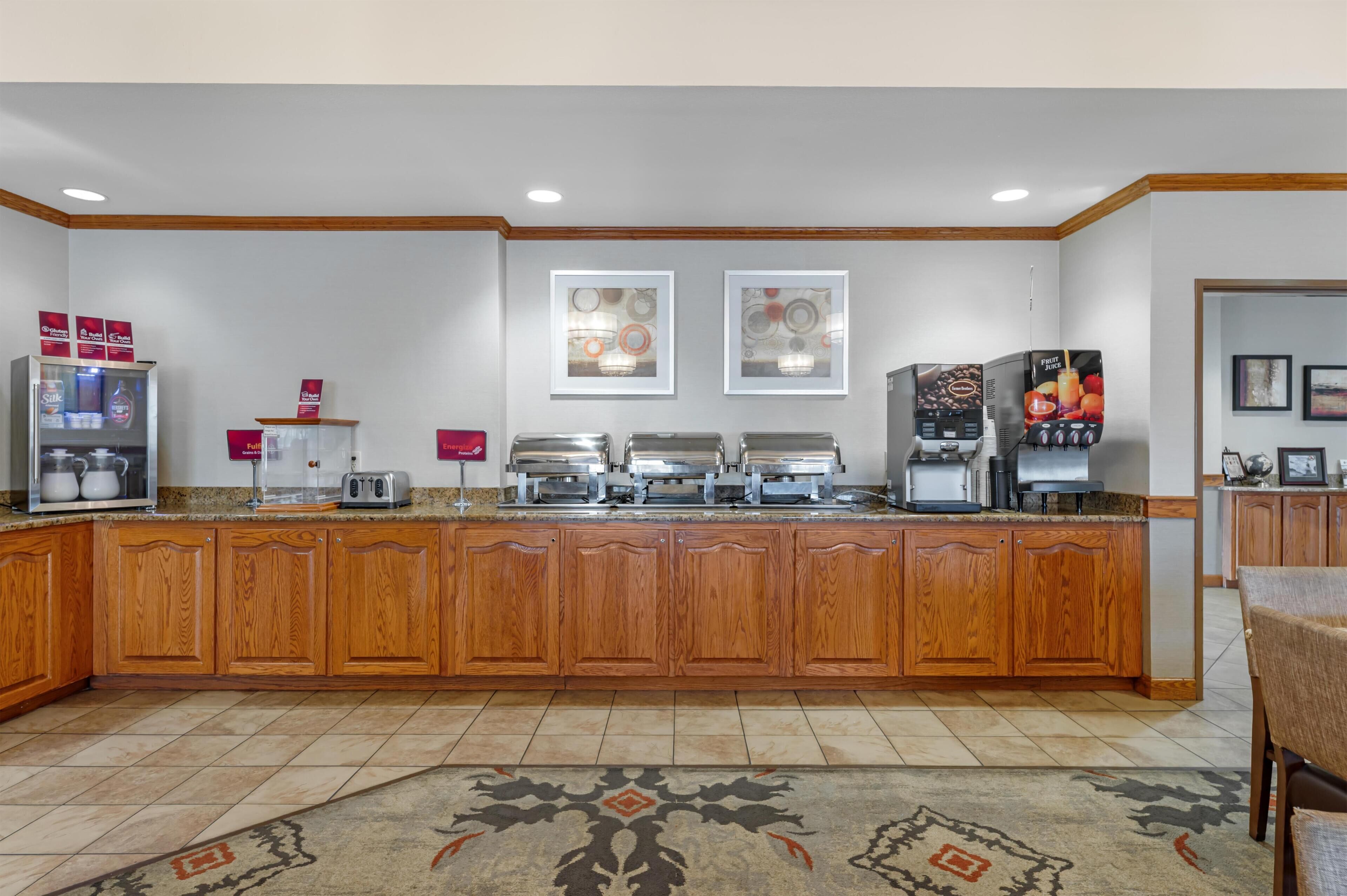 A kitchen with wooden cabinets, a refrigerator, a coffee machine, and a microwave.