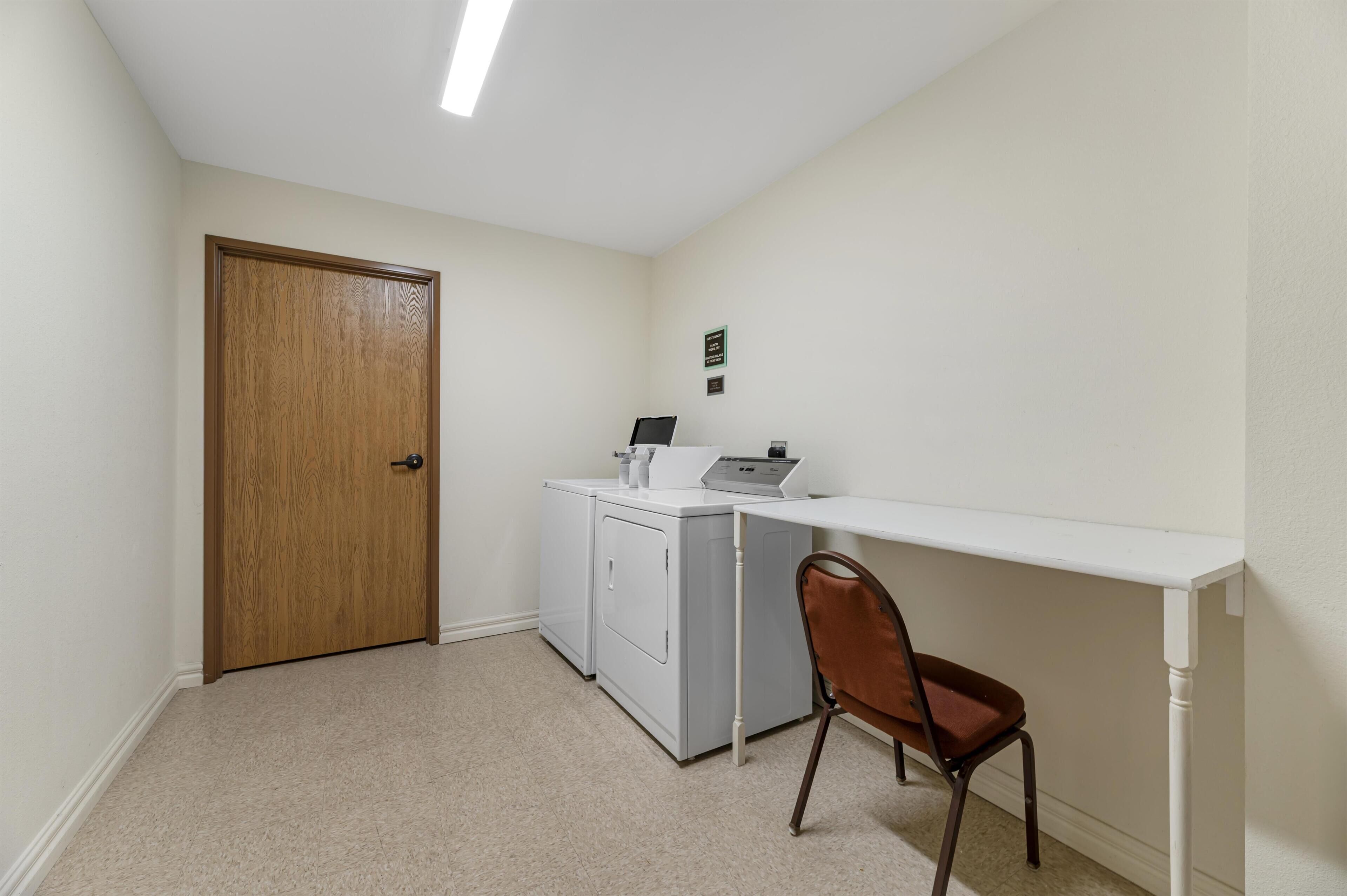 A laundry room with a washing machine, dryer, and a desk with a chair.