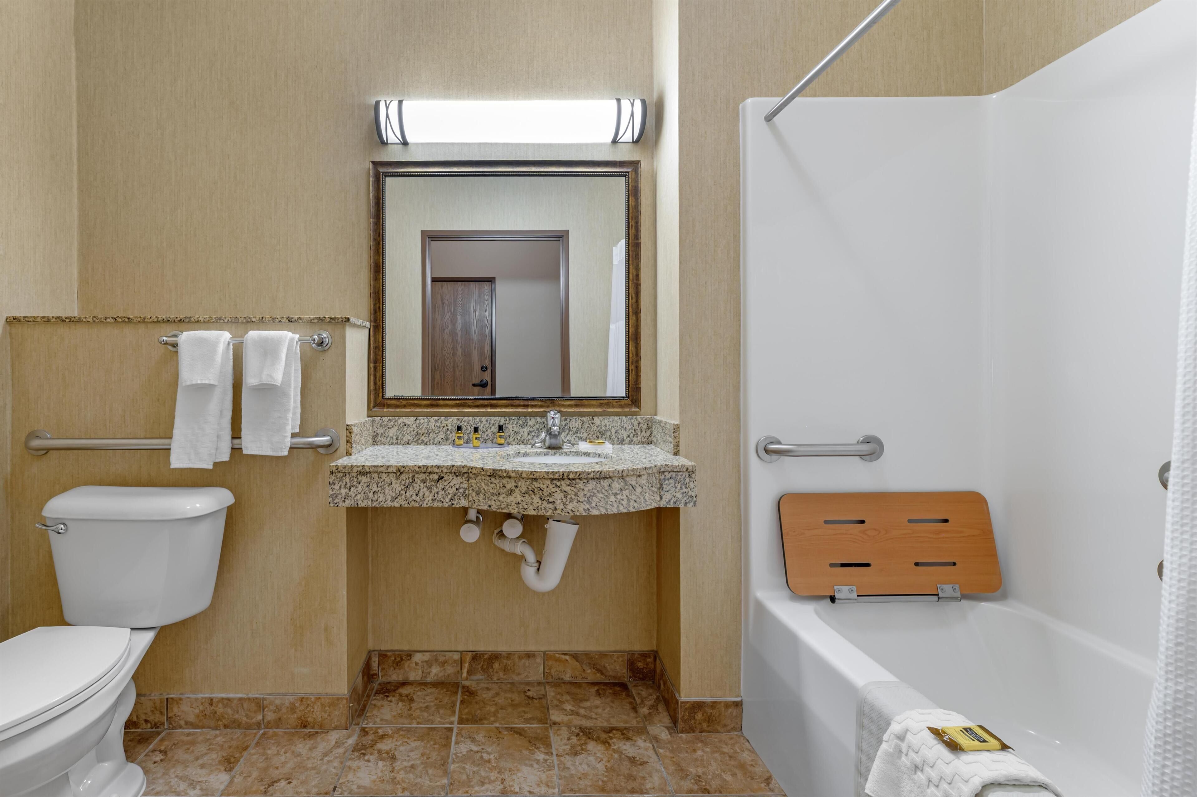 A bathroom with a toilet, sink, mirror, shower, and a towel rack.