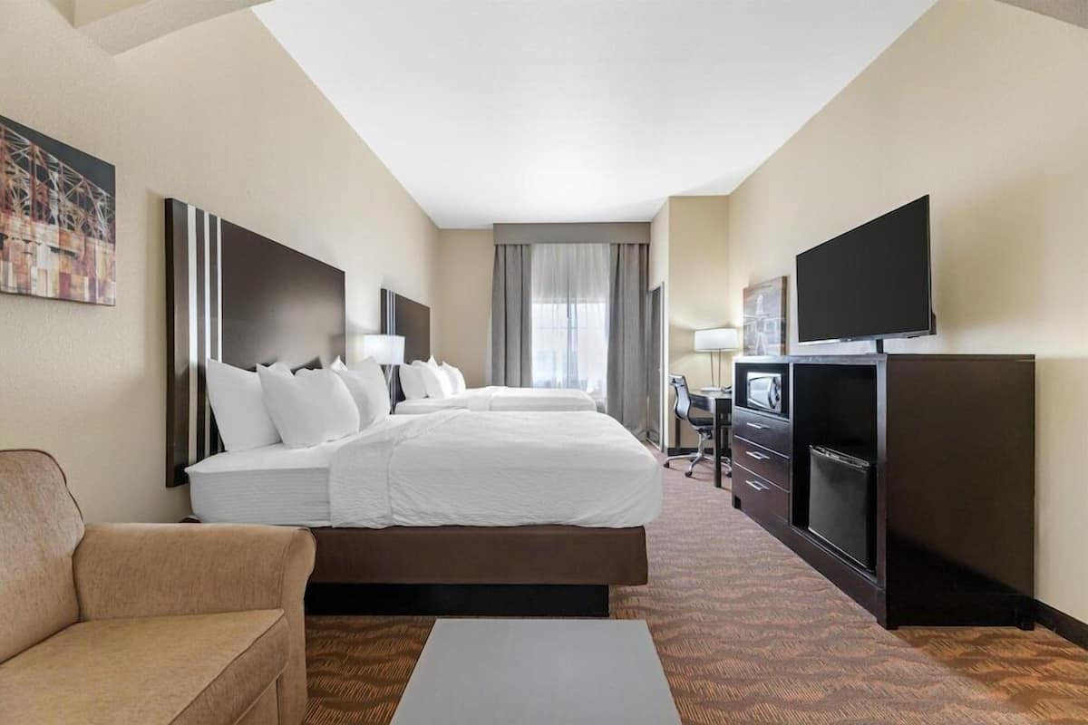 A hotel room with a large bed, a TV, a desk, and a couch.
