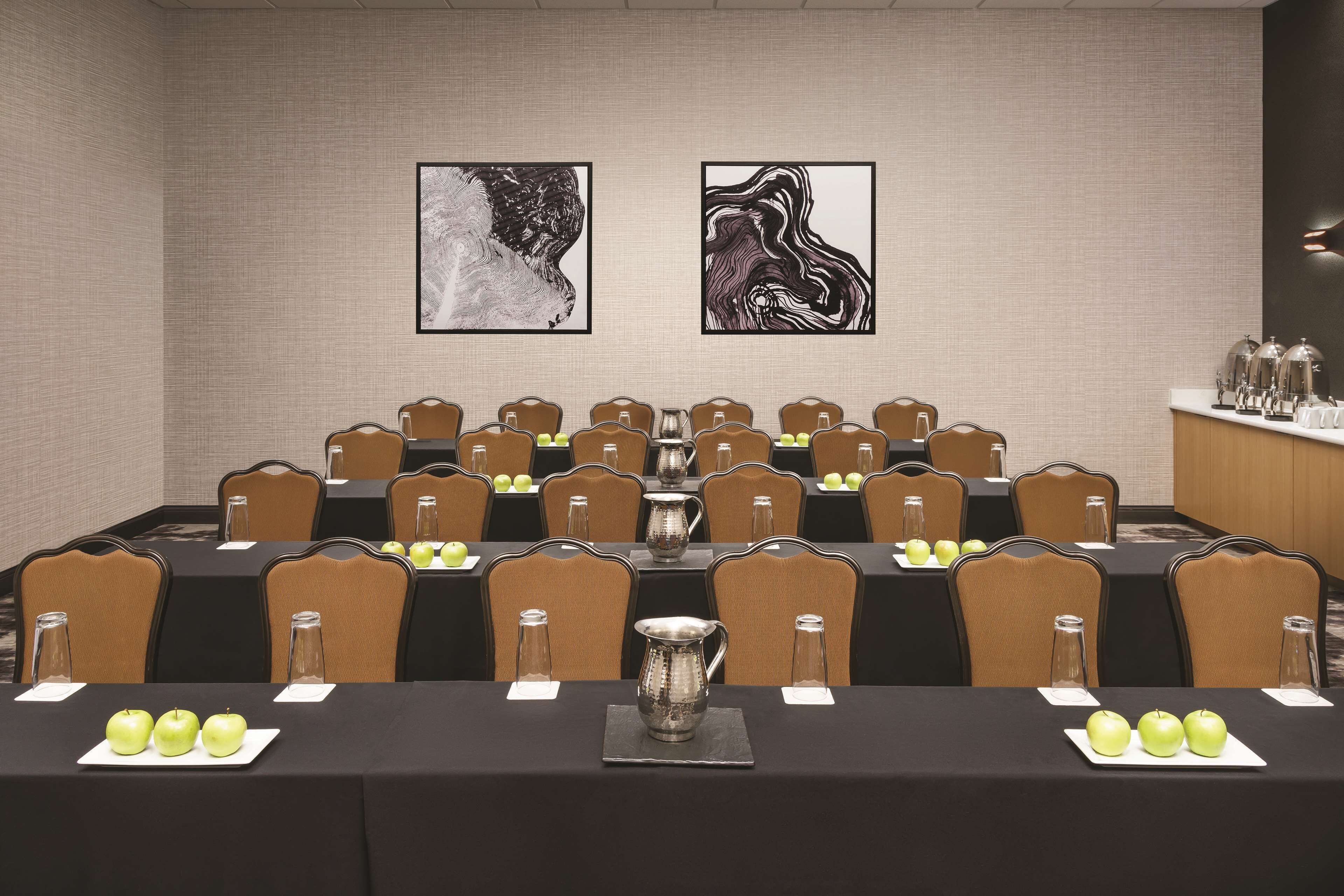 Une salle de conférence avec des tables disposées pour les réunions, équipée de chaises, de porte-noms et d’une carafe d’eau.