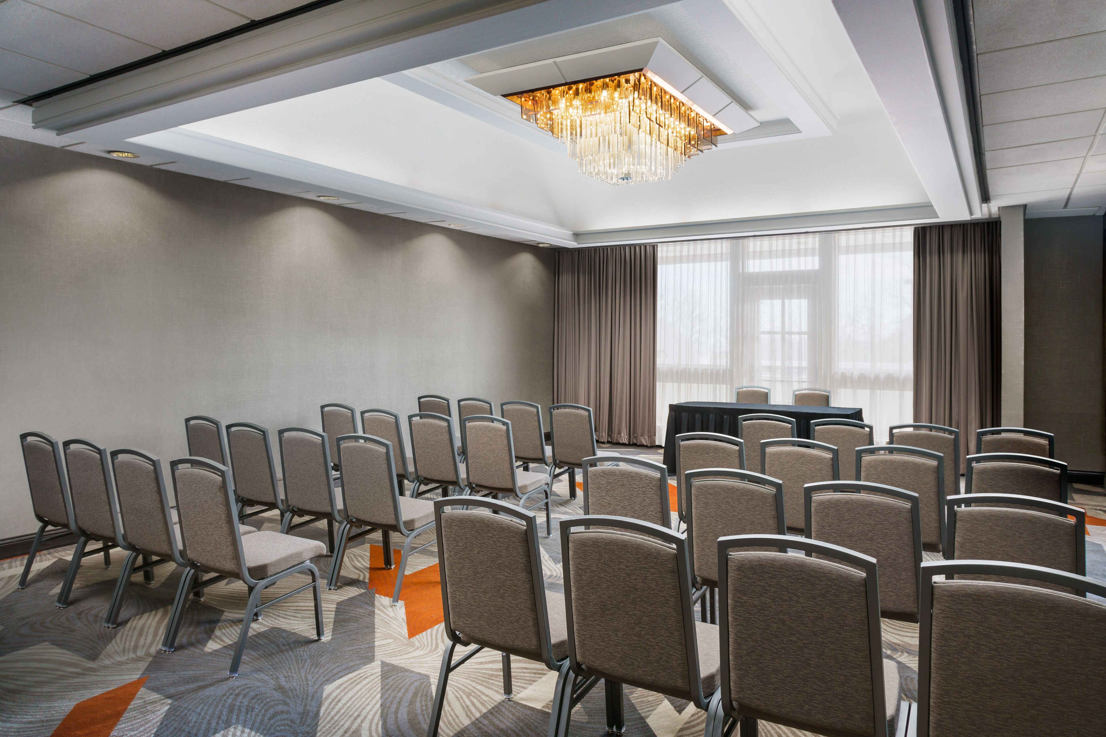 A conference room with rows of chairs, a large table, and a chandelier.