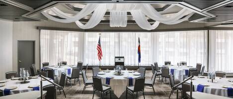 Un salón de conferencias con mesas redondas, sillas y banderas.