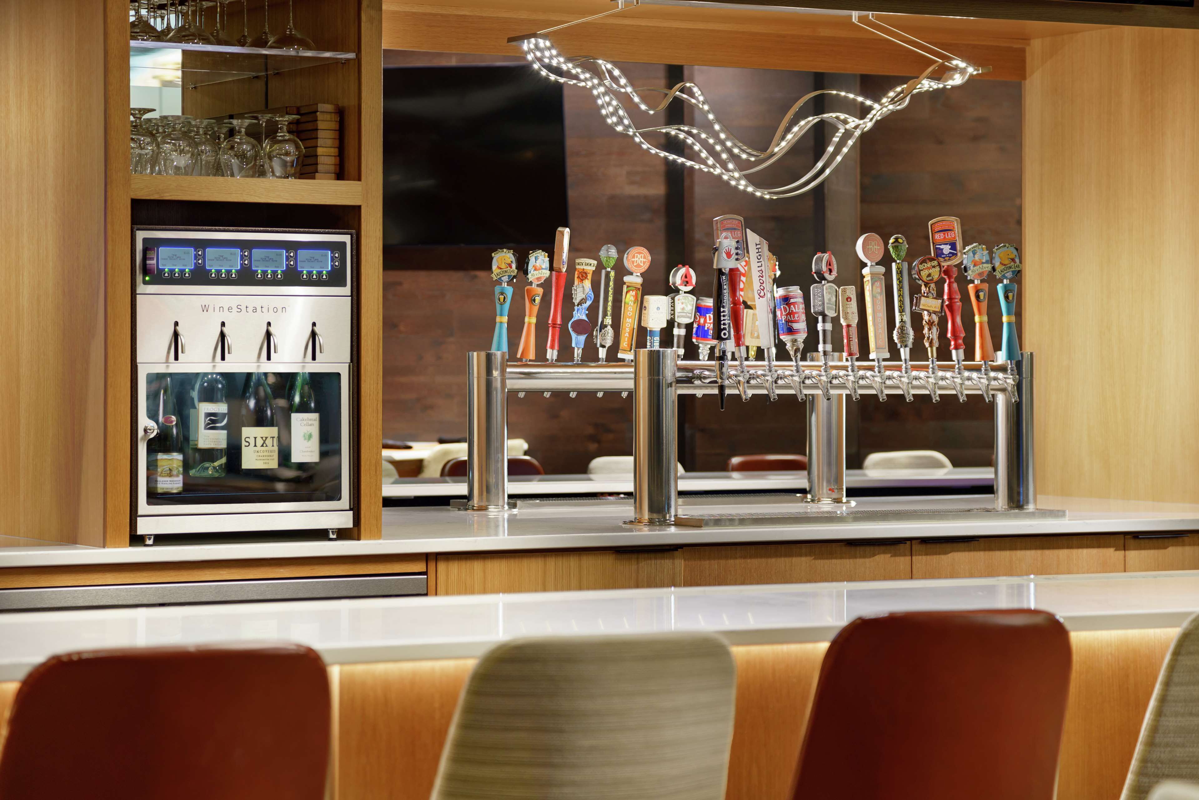 Un espace bar doté d’un distributeur de vin et de différents robinets à bière aux couleurs vives.