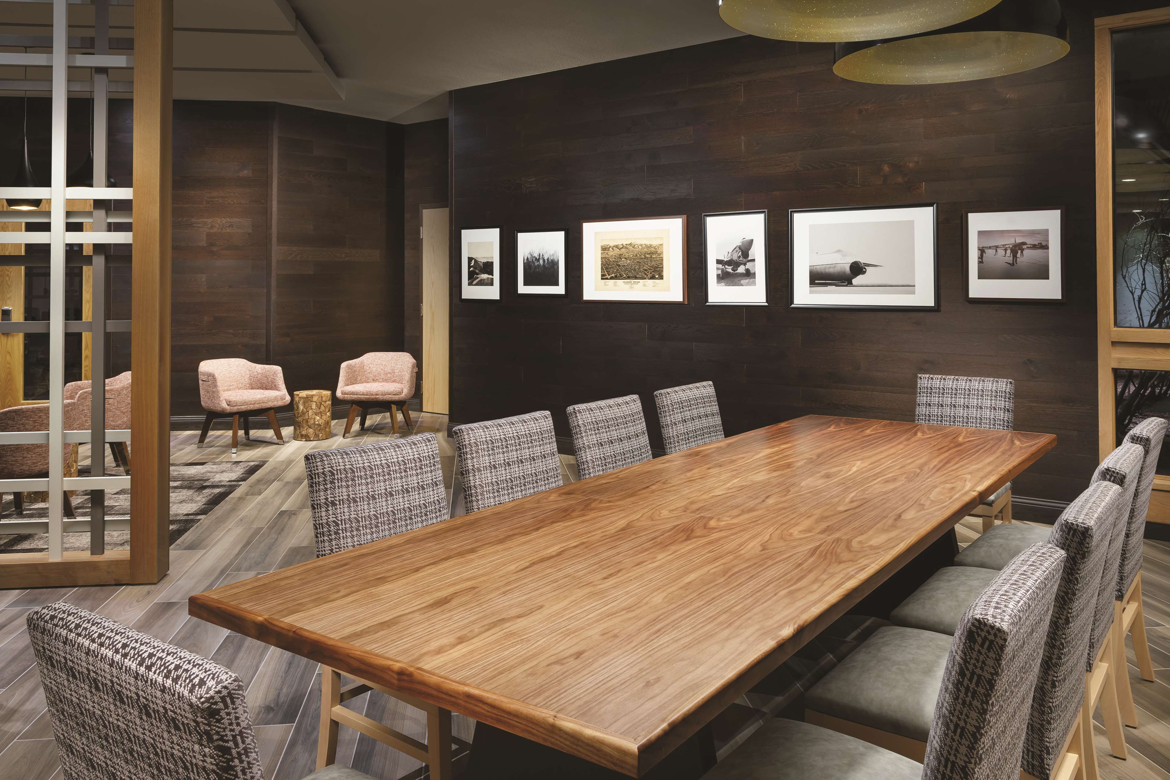 Une salle de conférence avec une longue table en bois, des chaises à motifs et des tableaux encadrés accrochés au mur.