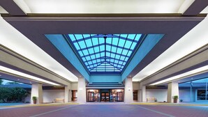 Een ruime inkomhal met glazen plafond, een bank in het midden en een symmetrisch ontwerp.