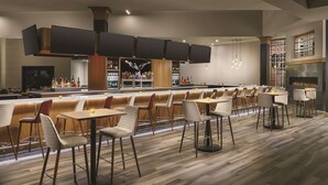Een moderne bar met diverse zitplaatsen, een bargedeelte en een open haard.