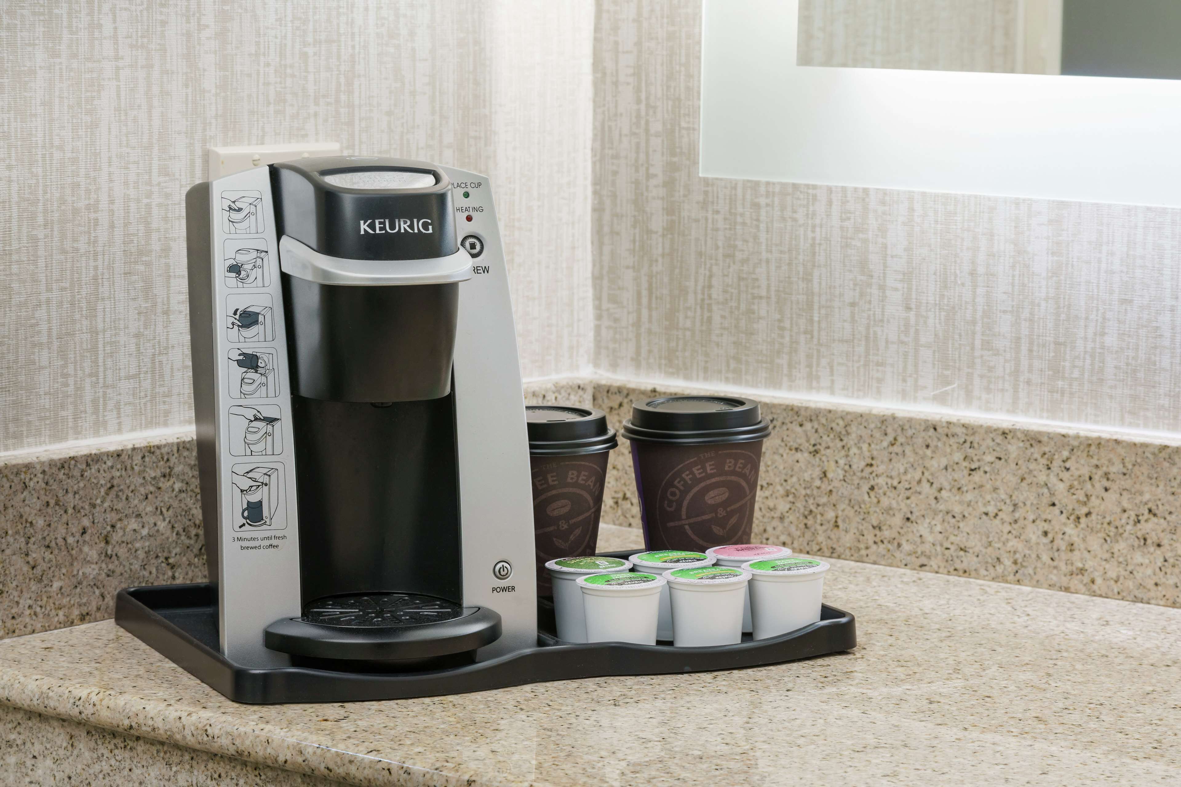 A Keurig coffee maker with a drip tray and several disposable coffee cups.