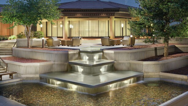 Een hotel met een waterpartij, terras en een gebouw met grote ramen.