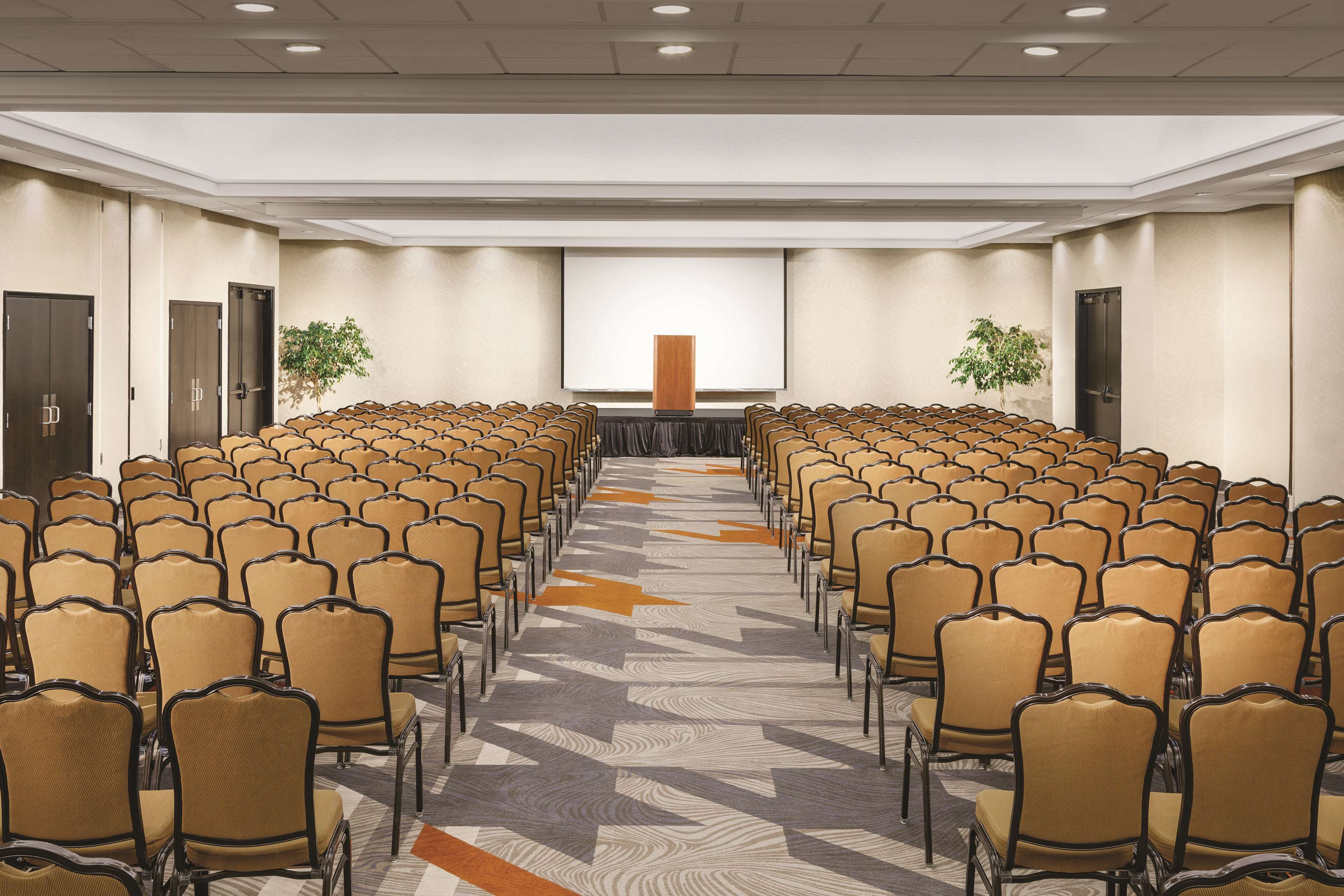 A conference room with rows of chairs facing a large screen at the front.