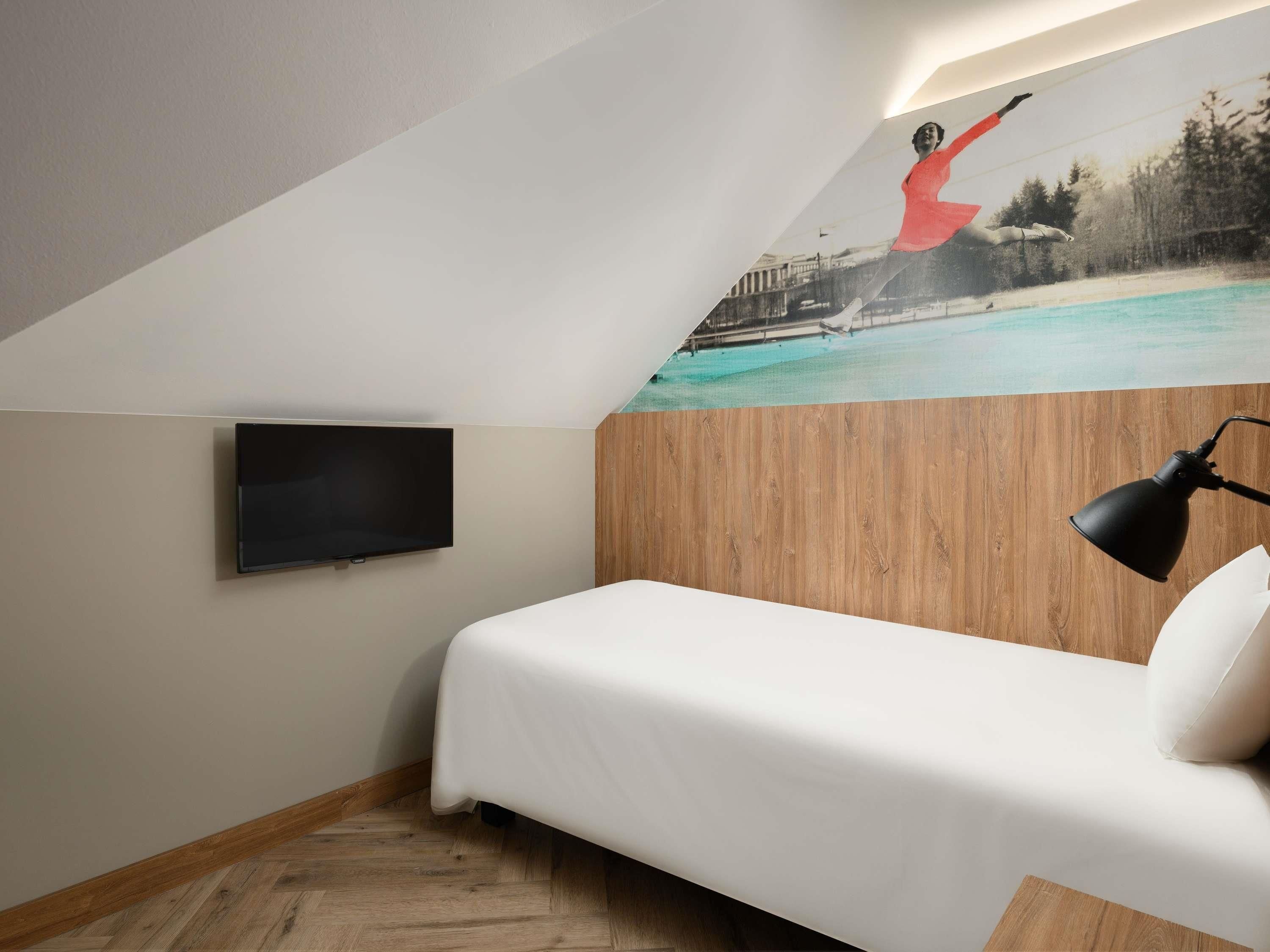 Ein Schlafzimmer mit Bett, Fernseher, Holzwand und Wandgemälde einer tauchenden Person.