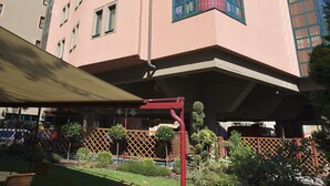 Ein mehrstöckiges Gebäude mit einer rosafarbenen Fassade, großen Fenstern und einer markanten roten Säule.