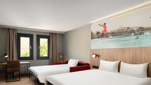 A hotel room with two beds, a desk, a chair, a lamp, and a painting on the wall. - ibis Styles Budapest Heroes Square (Budapest)