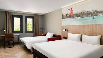 Habitación de hotel con dos camas, un escritorio, una silla, una lámpara y un cuadro en la pared.