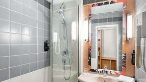 Uma casa de banho moderna com cabine de chuveiro em vidro, um lavatório com uma toalha e um espelho com moldura decorativa.