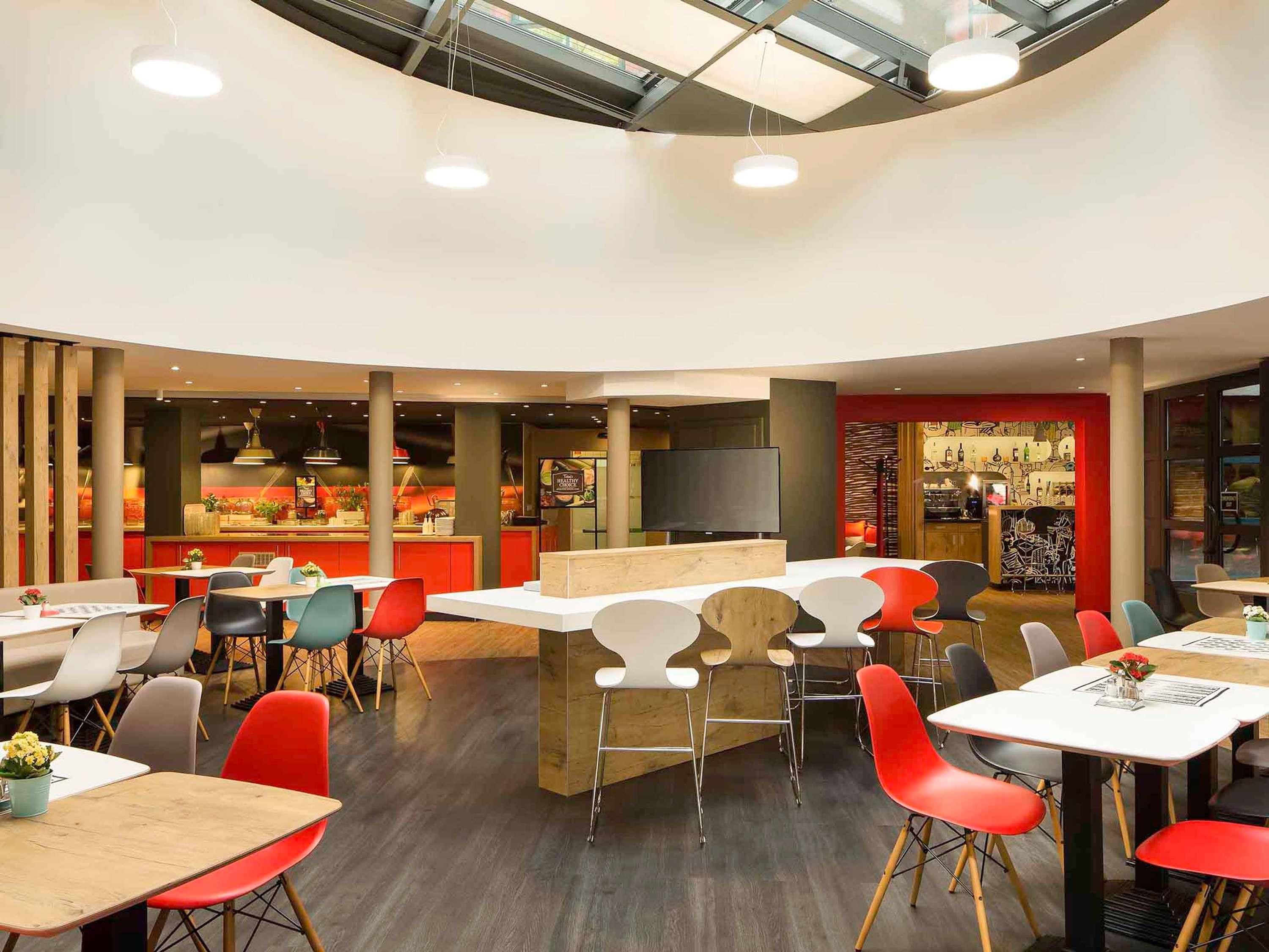 Un restaurante moderno con techo curvo, varias zonas de estar y una barra central.