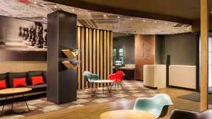 Ein moderner Lounge-Bereich mit Sitzgelegenheiten, einer Holzvertäfelung und einem wandmontierten Bildschirm.