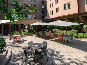 Un patio al aire libre con mesas y sillas, rodeado de edificios.