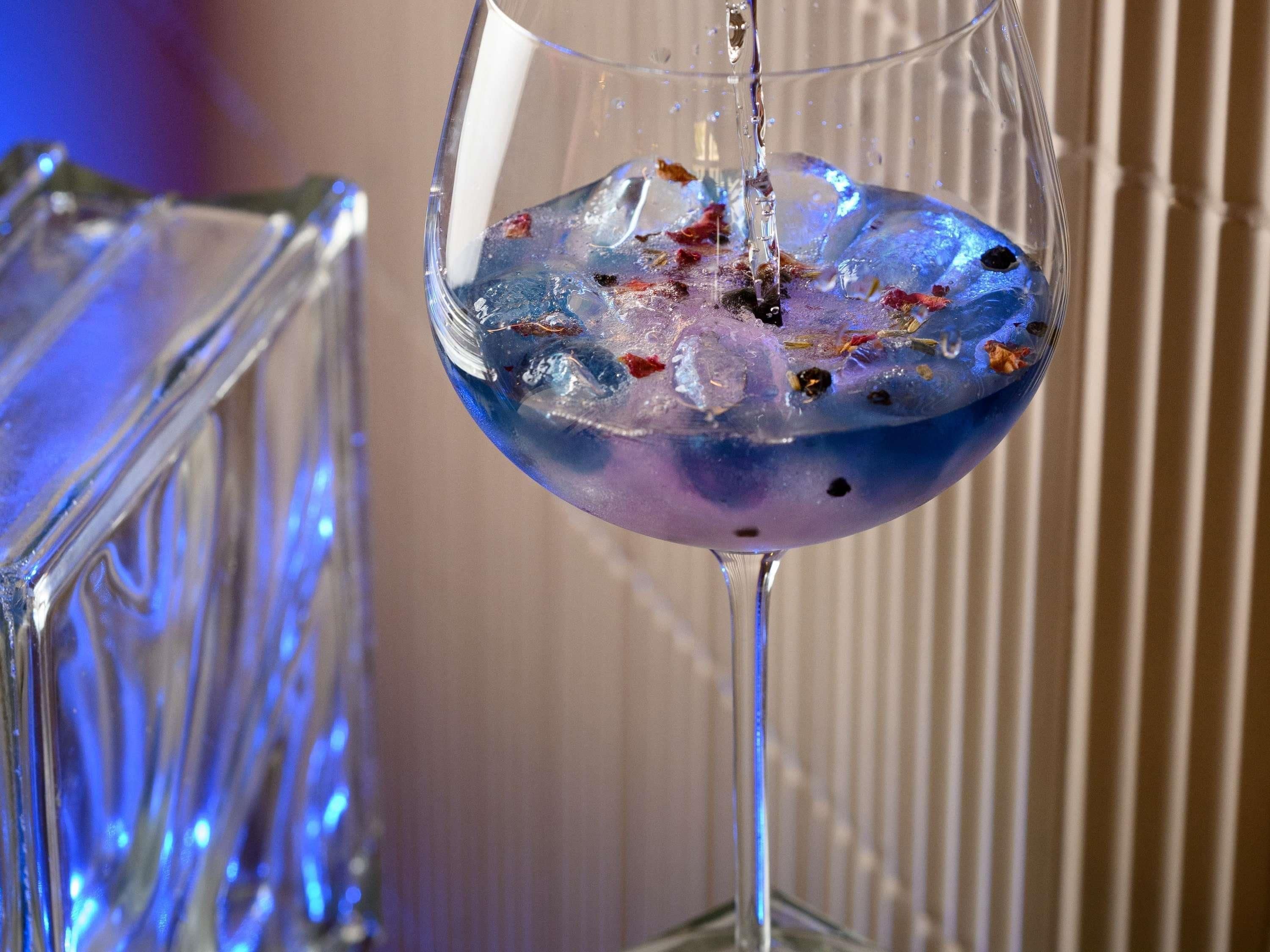 Un vaso con líquido azul y cubitos de hielo.