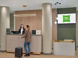 A reception desk with a digital screen displaying 'ibis Styles'.