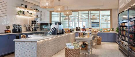 A modern kitchen with a central island, pendant lighting, and a view through large windows.
