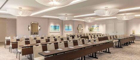 Une salle de conférence dotée de longues tables, de chaises et d’un éclairage moderne.