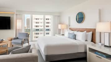 Quarto de hotel com uma cama grande, uma escrivaninha, uma cadeira e uma televisão.