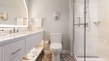 Une salle de bain moderne avec une douche à parois de verre, des toilettes blanches et un meuble-lavabo avec un miroir.