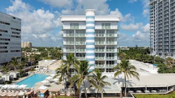 Experience the unique blend of modern architecture and tropical surroundings at this hotel, featuring a central tower and pool area with sun loungers.
