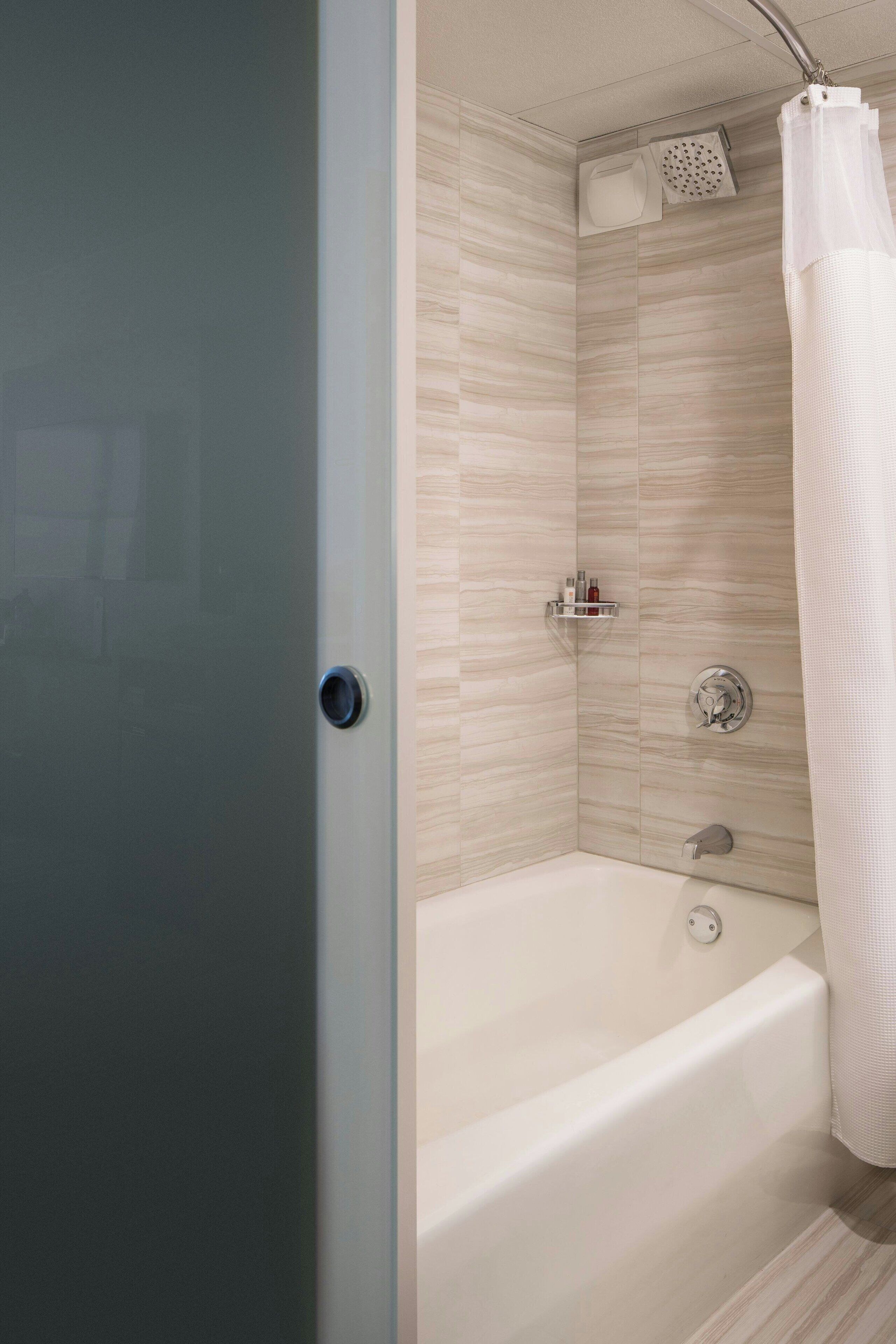 A modern bathroom with a bathtub, shower, and a toilet.